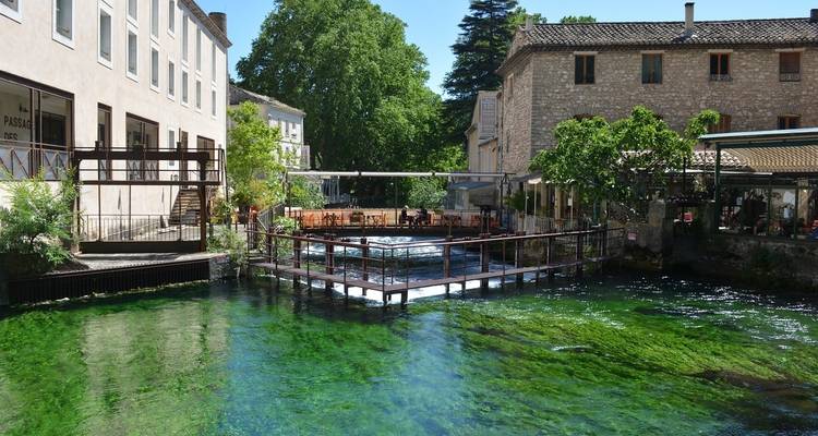 Outdoor restaurant area with clear water reflecting nearby buildings.