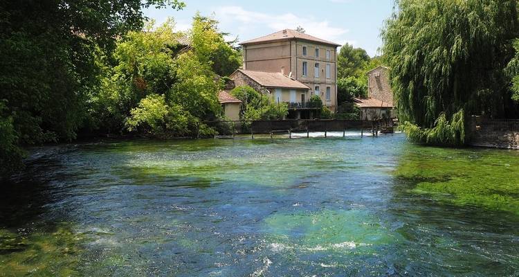 Scenic river with lush vegetation and a quaint building.