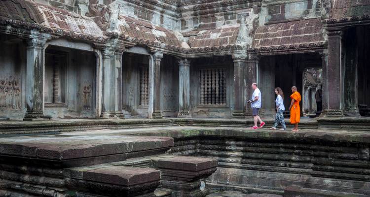 Visitors explore weathered stone corridors inside Angkor Wat temple.