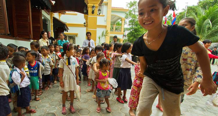 Excited schoolchildren line up in courtyard of Cambodian school.