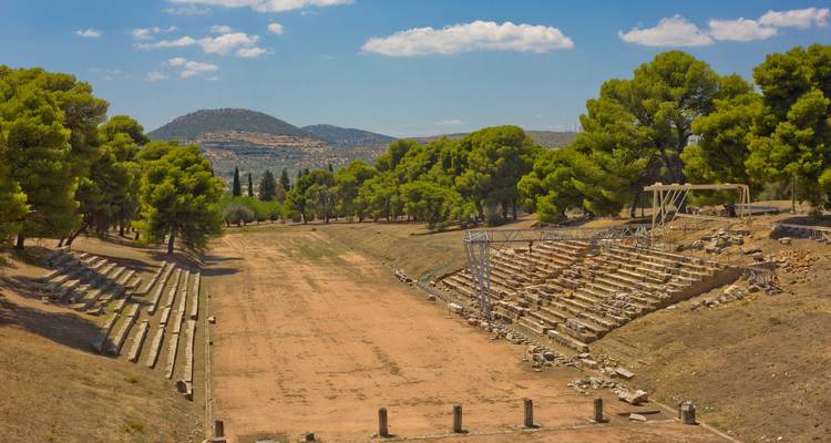 Ruines d'un ancien stade entouré d'arbres.