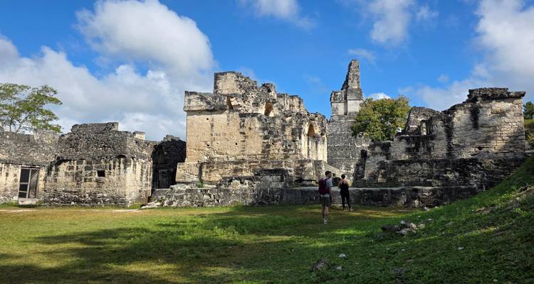 Bezoekers verkennen oude stenen constructies van een Maya-ruïnecomplex in de jungle
