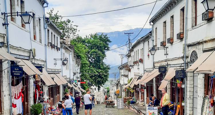Drukke kasseienstraat bazaar omzoomd met witte Ottomaanse gebouwen in Gjirokastra.