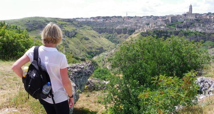 Femme avec un sac à dos admirant une vue panoramique d'une ville à flanc de colline.