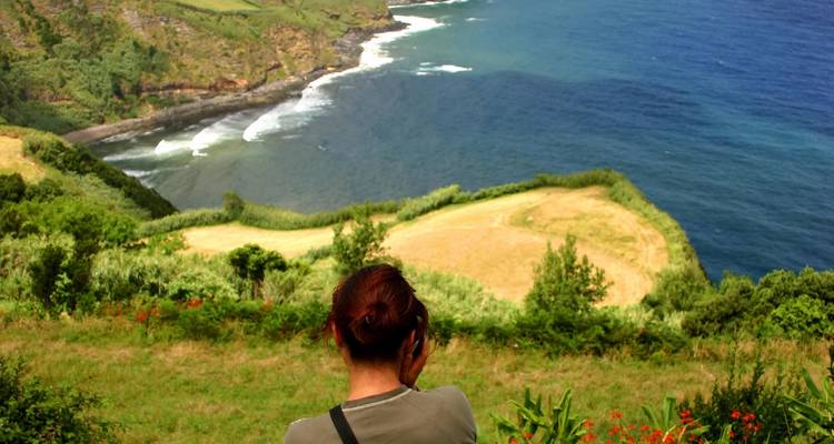 Una persona haciendo una fotografía de una vista panorámica de la costa.