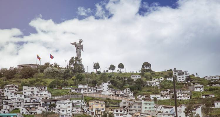 View of a hillside city with a large sculpture on top of the hill.