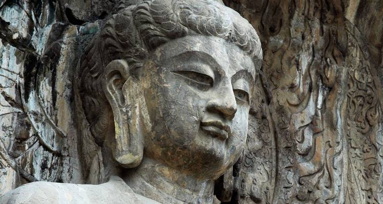 Primer plano de una escultura de piedra de Buda con tallados intrincados.