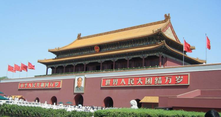 La Puerta de Tiananmen con banderas rojas y un gran retrato de una figura histórica.