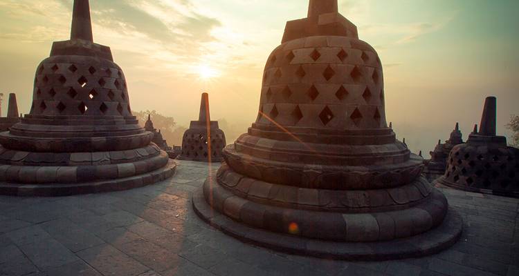Las estupas de piedra de Borobudur recortadas contra un cielo de salida del sol brumoso