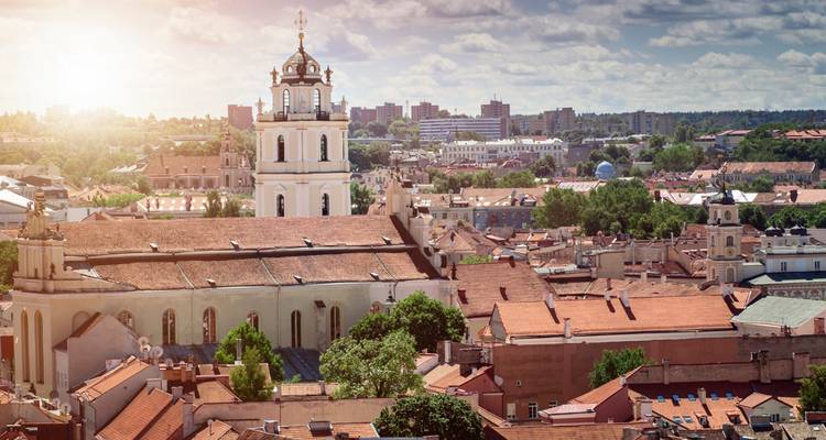 Les tours baroques de la vieille ville de Vilnius baignent dans la lumière chaude de l'après-midi au-dessus d'une mer de toits en terre cuite.