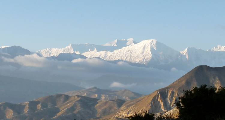 Los picos de nieve iluminados por el sol se elevan sobre capas de niebla y nubes bajas creando un paisaje espectacular.