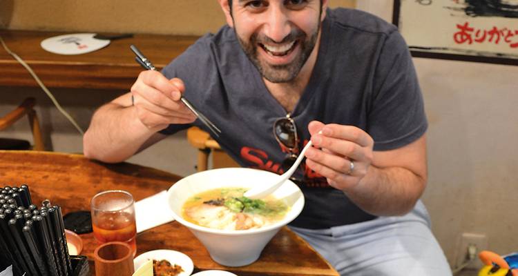 Eine Person, die eine Schüssel Ramen in einem gemütlichen Restaurant genießt.