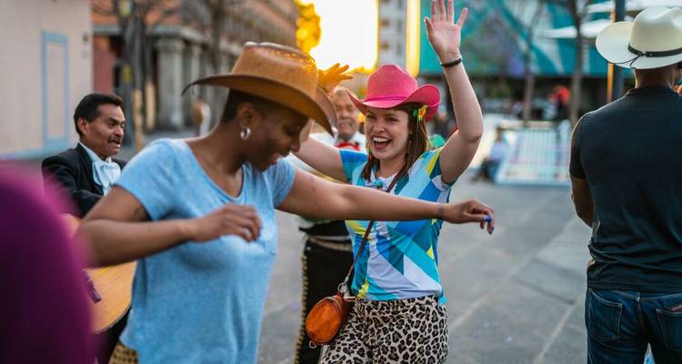 Personas con vestimenta colorida bailando al aire libre en un entorno urbano.