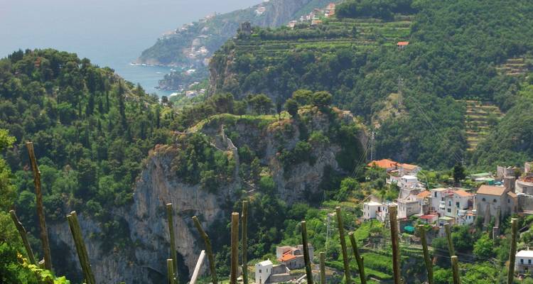 Cliffside village overlooking a blue ocean with terraces and greenery.