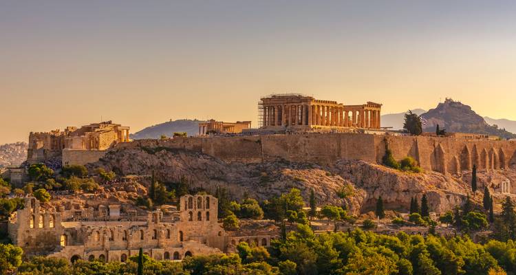Warme Sonnenuntergangstoene erleuchten die Akropolis und die umgebenden Ruinen über Athen.
