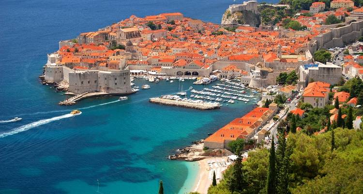 Luftaufnahme von Dubrovnik mit einer ummauerten Altstadt und klarem blauem Meer.