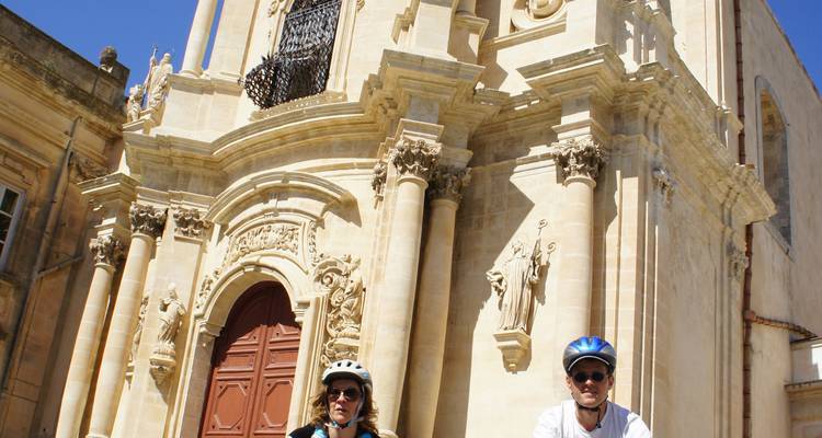 Dos ciclistas delante de una catedral ornamentada