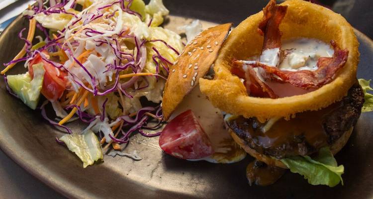 Bord met eten met een hamburger en salade.