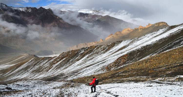 Personne effectuant une randonnée dans un paysage de montagne enneigée.