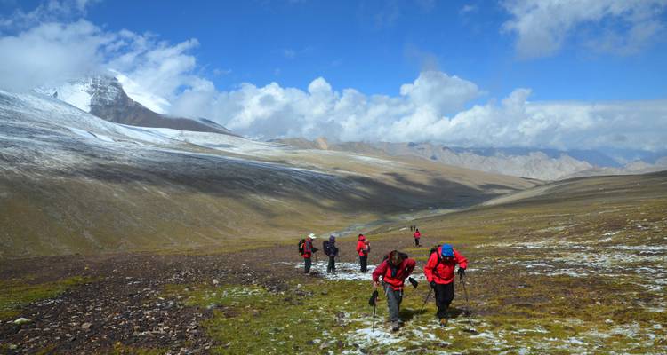 Randonneurs en veste rouge sur fond de montagne enneigée.