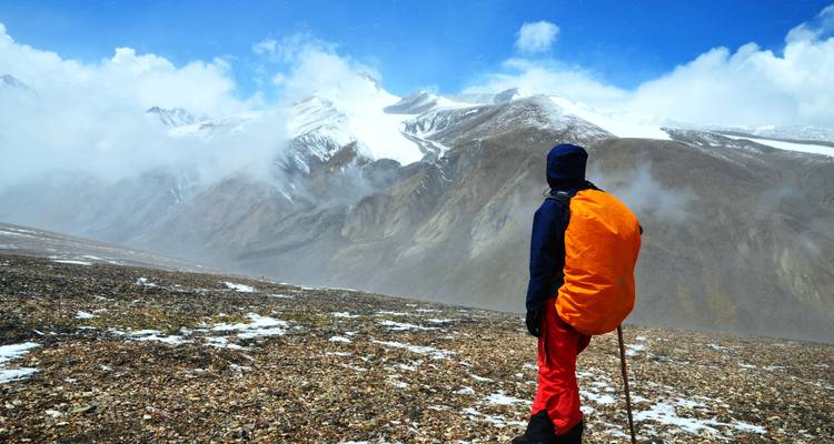 Personne debout admirant la chaîne de montagnes enneigées.