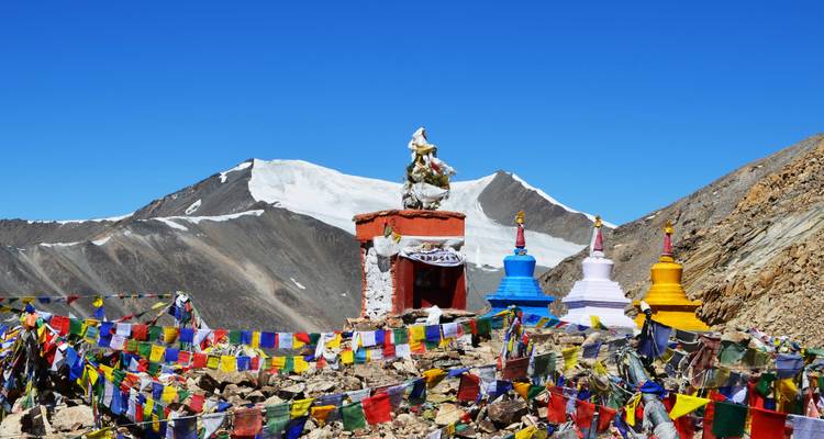 Paysage de montagne avec des drapeaux de prière colorés et des stupas.
