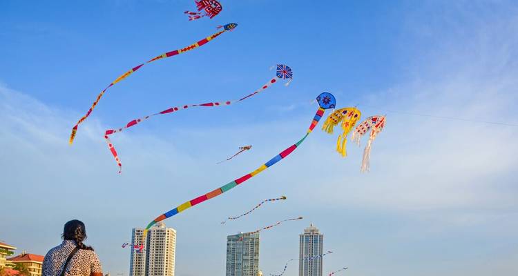 Personne faisant voler des cerfs-volants colorés dans un paysage urbain avec de grands immeubles.