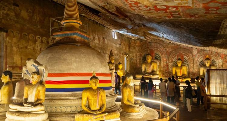 Interior del Templo de la Cueva de Dambulla lleno de estatuas doradas de Buda y murales coloridos.