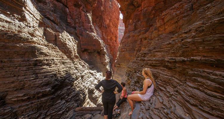 Los viajeros descansan en repisas de roca estratificada en las profundidades de un desfiladero estrecho e iluminado por el sol.