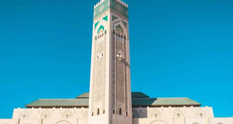 Das hohe Minarett der Hassan-II-Moschee erhebt sich gegen einen klaren blauen Himmel.