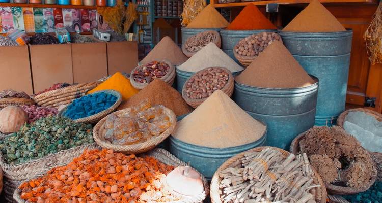 Étal vibrant du souk marocain avec des épices colorées entassées dans des seaux et des paniers en métal.