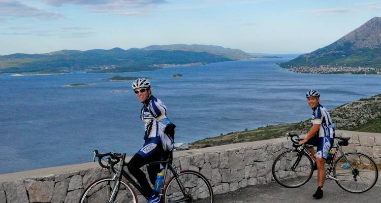 Deux cyclistes posant à un point de vue avec mer et îles.