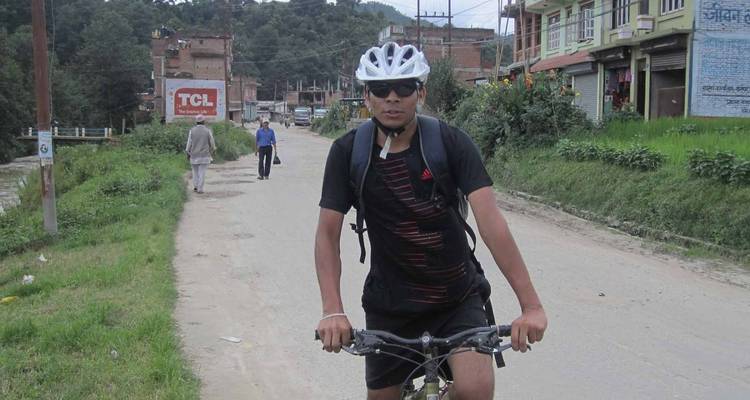 Fietser met zonnebril op een weg in een landelijke omgeving.