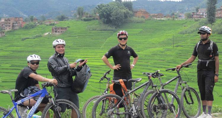 Groep fietsers poseert voor weelderige, groene velden.