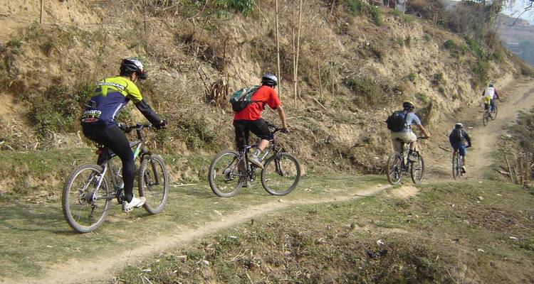 Groep fietsers op een smal zandpad.