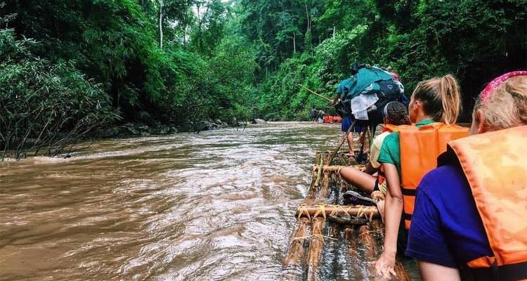 Groupe de personnes faisant du rafting sur une rivière à travers une jungle.