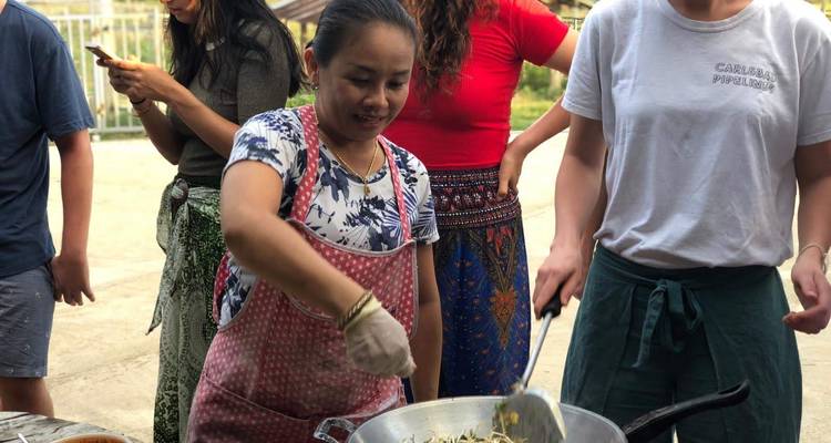 Des gens cuisinent ensemble avec une femme qui remue une casserole.