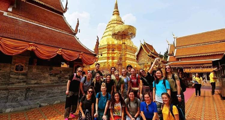 Grand groupe de personnes posant devant un temple doré.