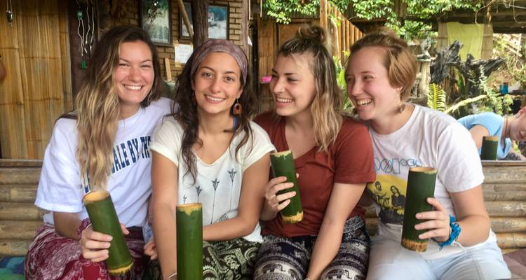 Quatre femmes souriantes tenant des tasses en bambou.