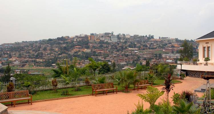 Elevated view of Kigali’s rolling hills dotted with buildings and greenery under a hazy sky.