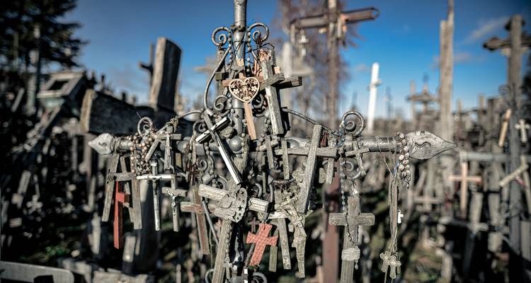 Numerosas cruces y símbolos religiosos en una colina bajo un cielo azul.
