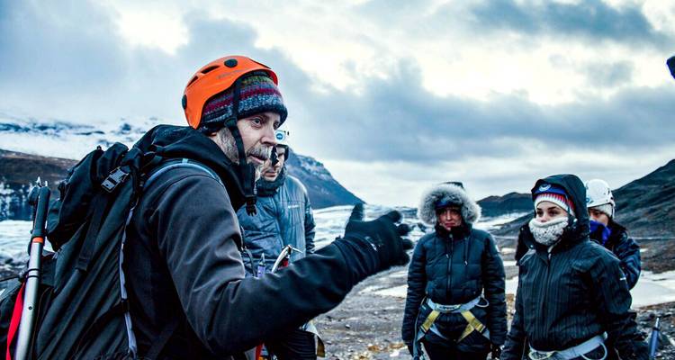 Instructor hablando a un grupo de personas con ropa de invierno en un glaciar.