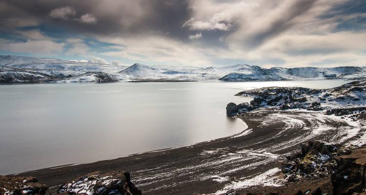 Paysage de lac gelé sous un ciel dramatique.