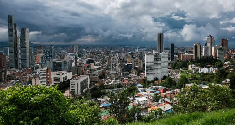 Dramatic skyline of a sprawling city with storm clouds over mountain backdrop.