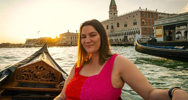 Mujer disfrutando de un paseo en góndola por un canal con arquitectura histórica.