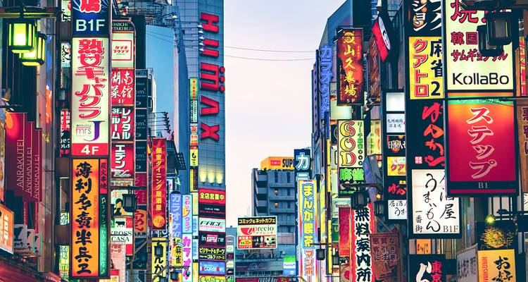 Le canyon de gratte-ciel illuminés au néon de Tokyo brille au crépuscule avec une signalétique japonaise colorée qui s'étend vers le ciel.