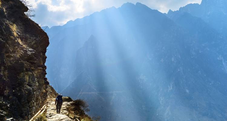 Excursionista en un sendero del acantilado bañado por rayos de sol dramáticos en la Garganta del Tigre Saltarín.