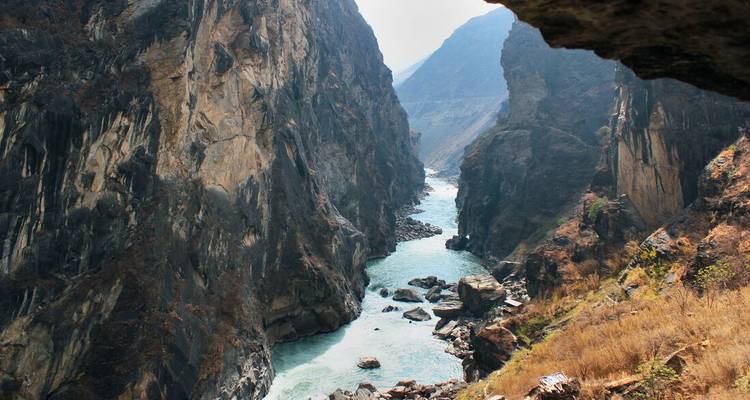 Desfiladero rocoso escarpado con un río turquesa serpenteando entre acantilados imponentes.