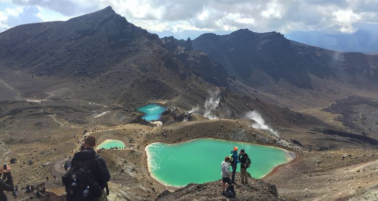 Wanderer, die smaragdgrüne Seen in einer bergigen Gegend überblicken.