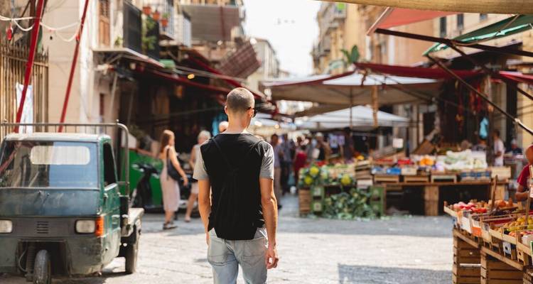 Rue animée du marché en plein air à Palerme avec des étals de produits.